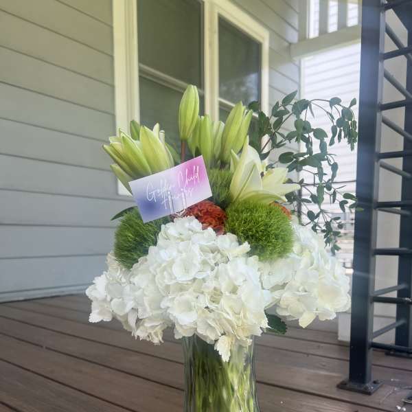 White hydrangeas and lilies arranged in a glass vase