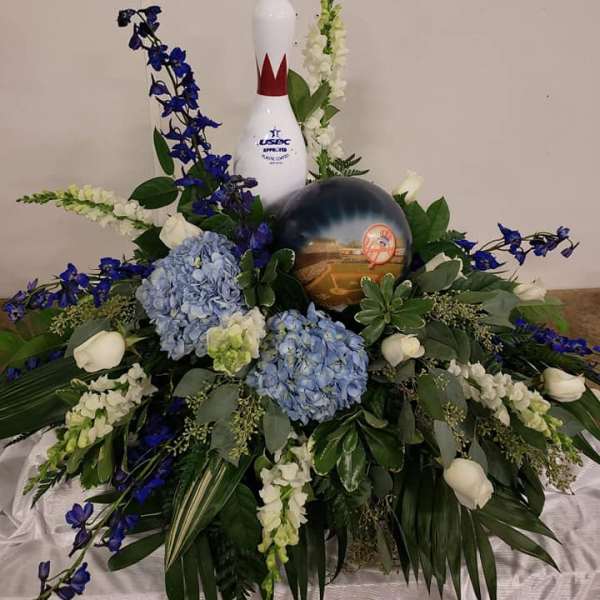 Floral arrangement with blue and white flowers around a bowling pin and ball