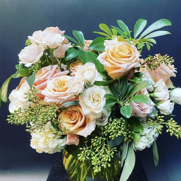 Peach and white roses arranged in a glass vase