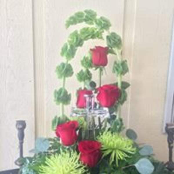Tall arrangement of red roses with green foliage around a silver stand