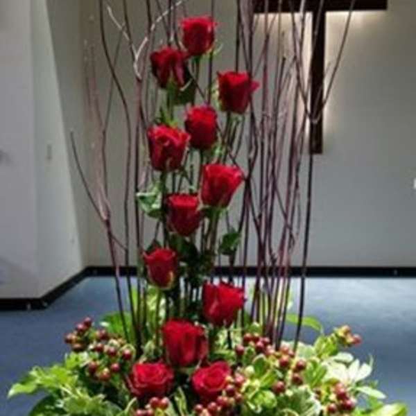 Tall arrangement of red roses with greenery in a vase