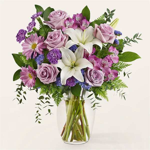 Lavender roses and white lilies in a clear glass vase