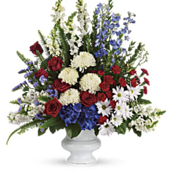 Red roses, white mums, and blue flowers in a white vase