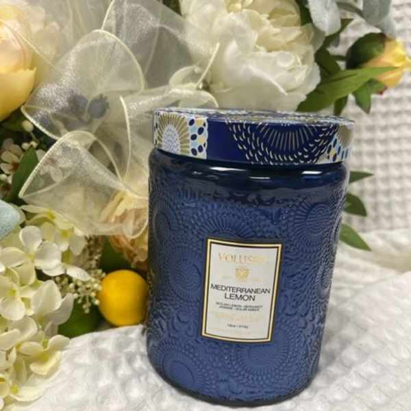Blue candle jar beside a white floral arrangement with yellow lemons