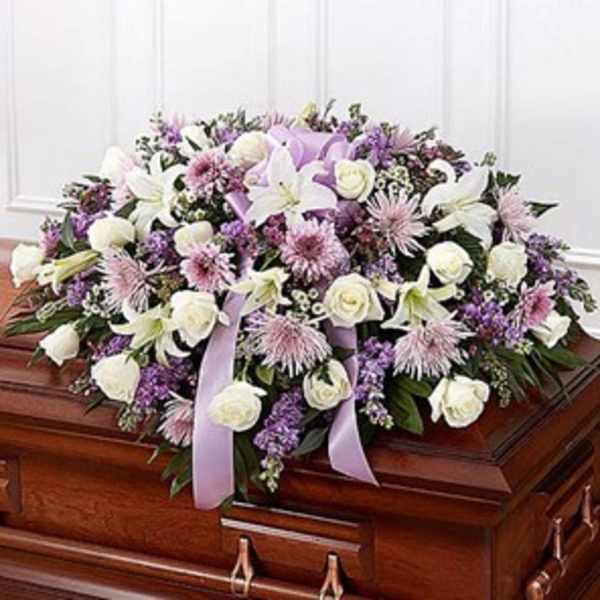 Lavender and white floral spray on a wooden casket