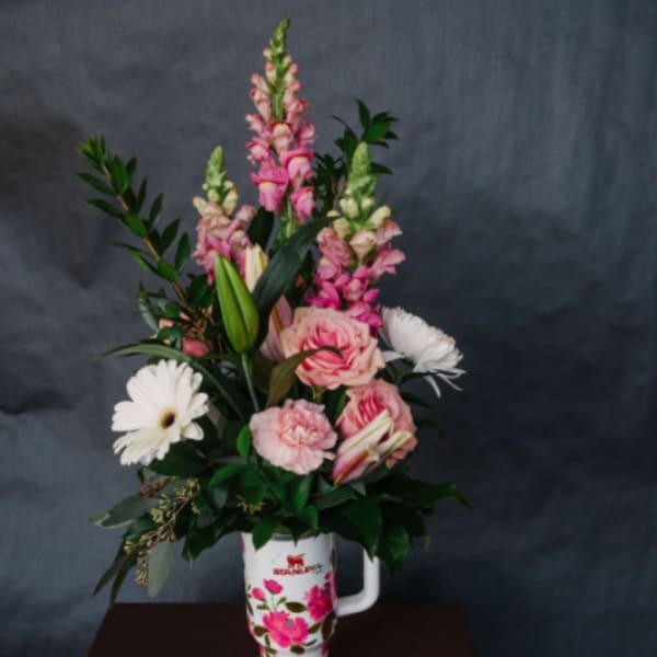 Pink and white flowers arranged in a floral tumbler