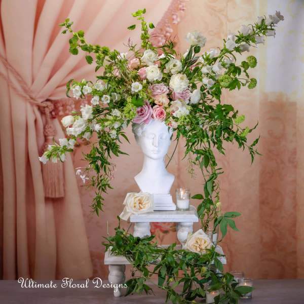 Floral arrangement with pink and white roses on a white bust pedestal