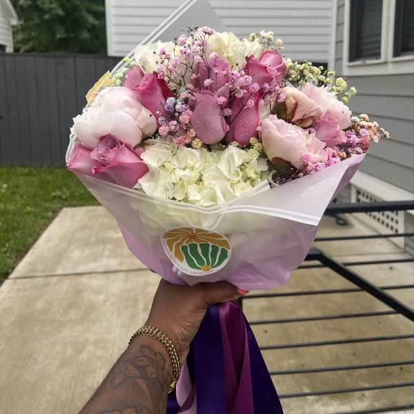 Pink and white bouquet of roses, hydrangeas, and baby's breath wrapped in pastel paper