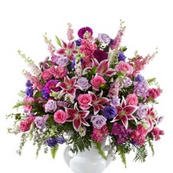 Mixed pink and purple flower arrangement in a white vase