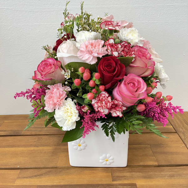 Pink and white rose and carnation arrangement in a white square vase