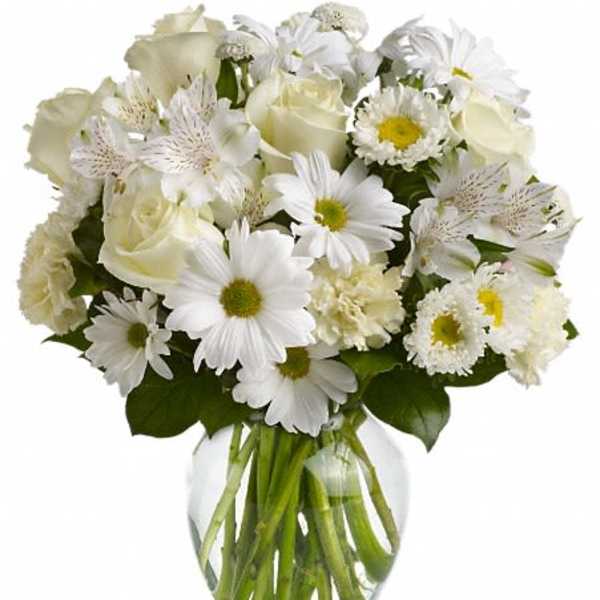 White bouquet of roses and daisies in a clear glass vase