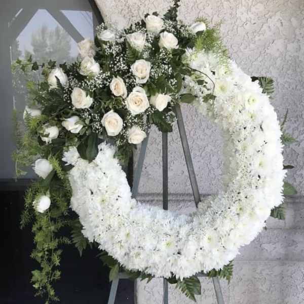 White rose and chrysanthemum funeral wreath on an easel