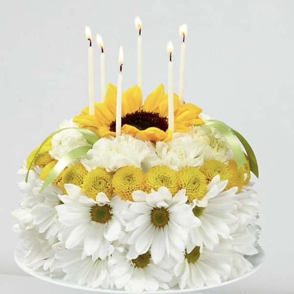 Flower cake with candles and white daisies on a pedestal stand