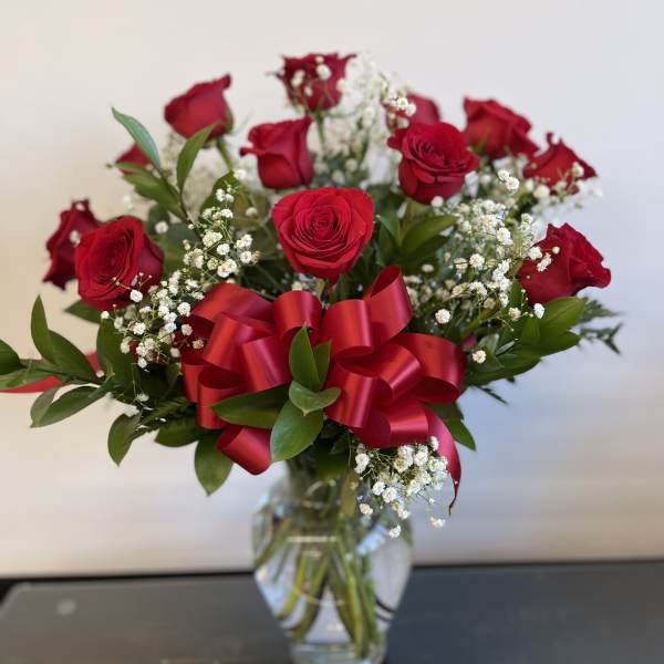 Red roses in a clear glass vase with a red ribbon bow