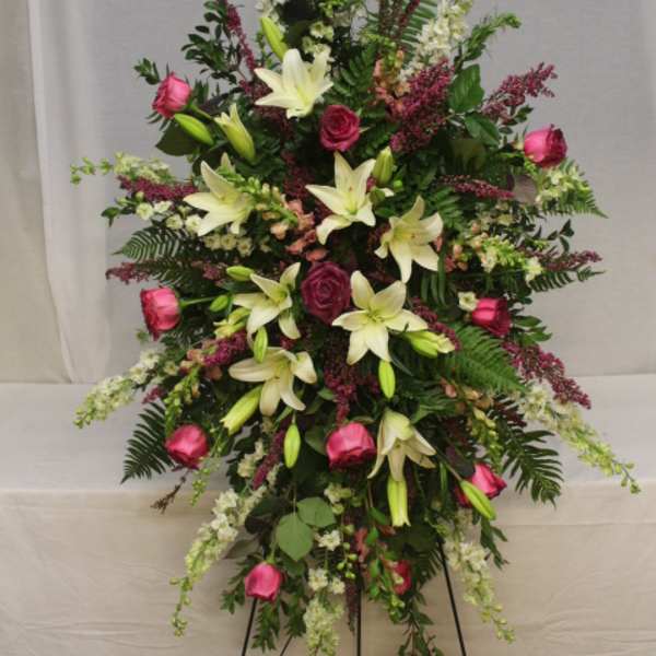 Standing floral spray with pink roses and white lilies on a black easel