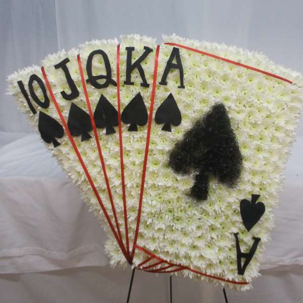 Fan-shaped white floral tribute with playing card symbols and letters