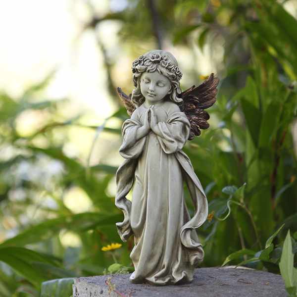 Small angel statue with folded hands on a stone surface