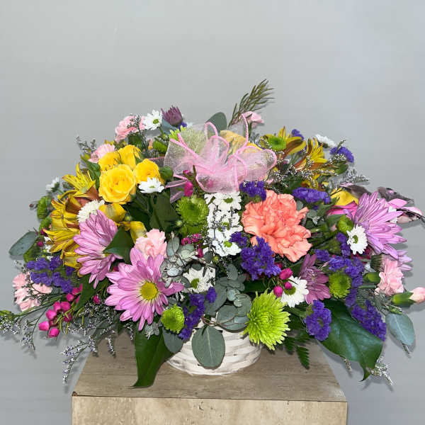 Mixed bouquet in a white basket with pink ribbon and colorful flowers