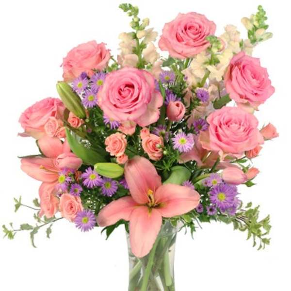 Pink roses, lilies, and purple asters arranged in a clear glass vase