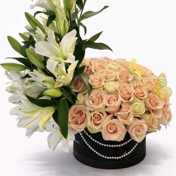 White lilies and peach roses in a black round box with pearl trim