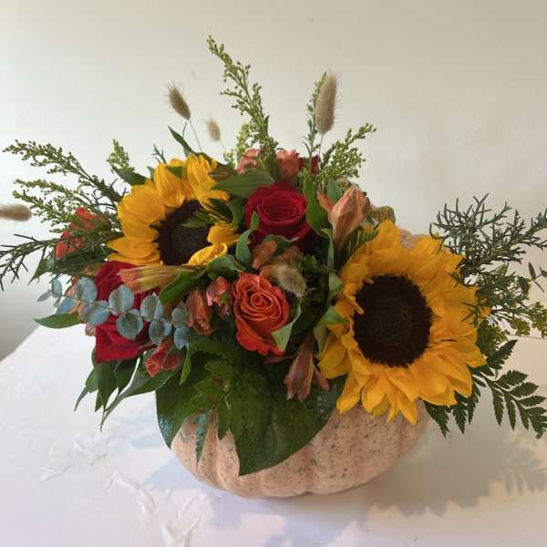 Sunflowers and roses arranged in a pumpkin-shaped container