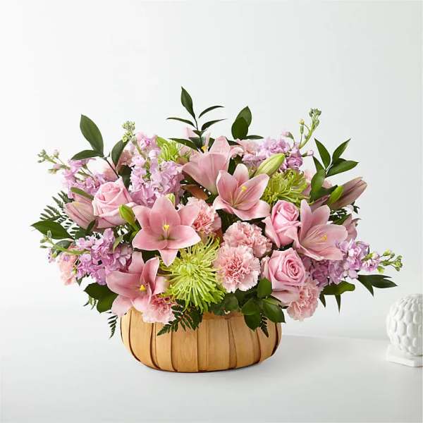 Pink lilies and roses in a woven basket arrangement