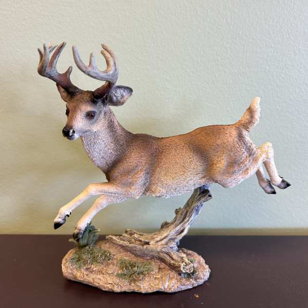 Decorative deer figurine leaping on a faux wood base