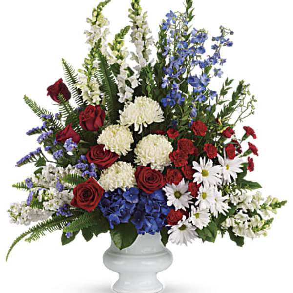 Mixed red, white, and blue floral arrangement in a white vase