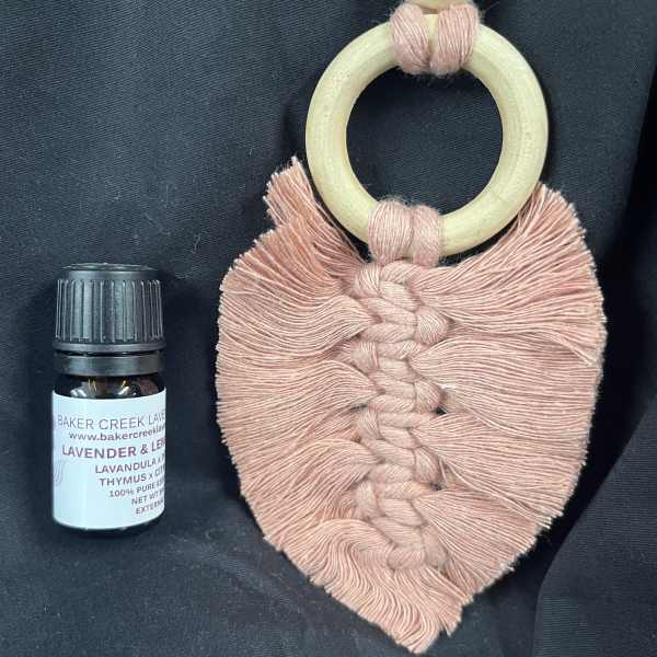 Macrame wall hanging and a small essential oil bottle on dark fabric