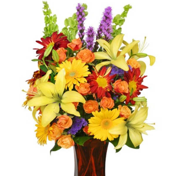 Tall mixed bouquet of yellow lilies, gerbera daisies and orange roses in an amber glass vase