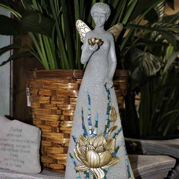 Decorative angel statue with mosaic flower detail beside a woven planter