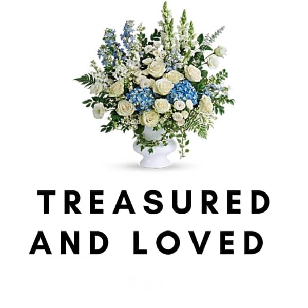 White and blue floral arrangement in a white vase with memorial text below