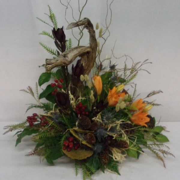 Autumn floral arrangement with orange blooms, berries, and driftwood