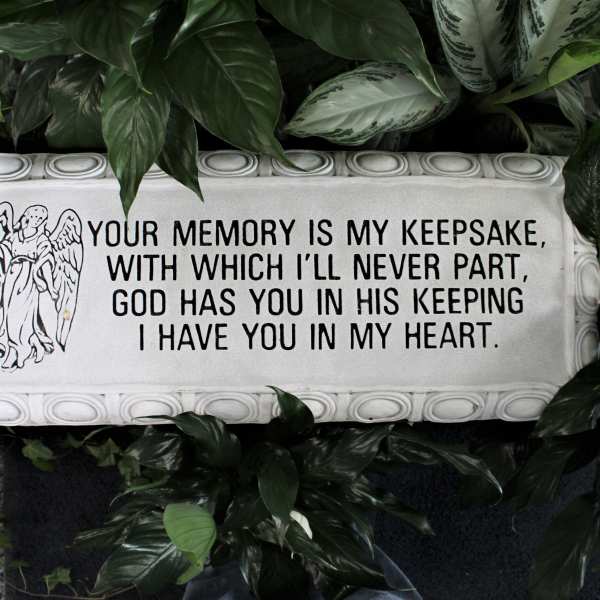 Memorial plaque with an angel and sympathy message surrounded by foliage