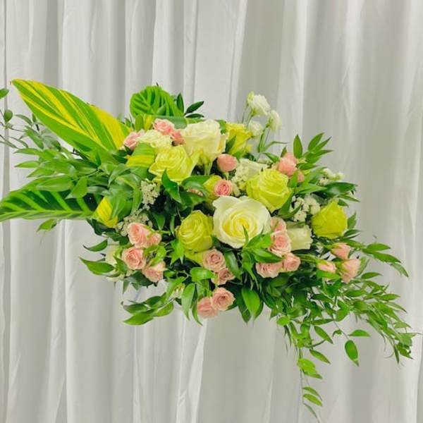 Large floral arrangement with yellow and pink roses and lush greenery