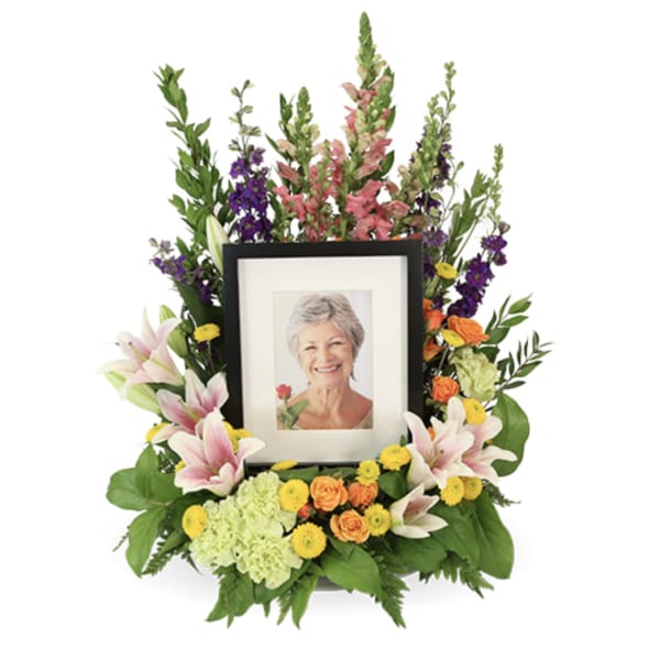Framed photo surrounded by a colorful floral tribute arrangement