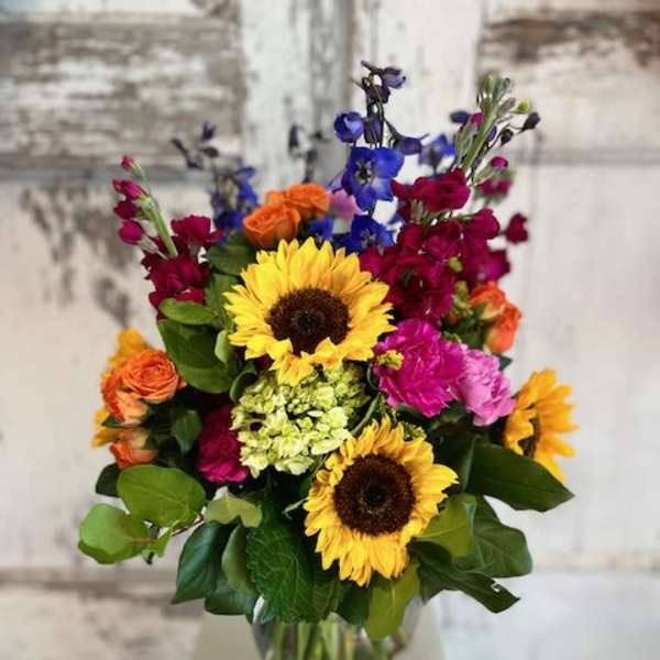 Mixed bouquet with sunflowers, roses, and colorful blooms in a glass vase
