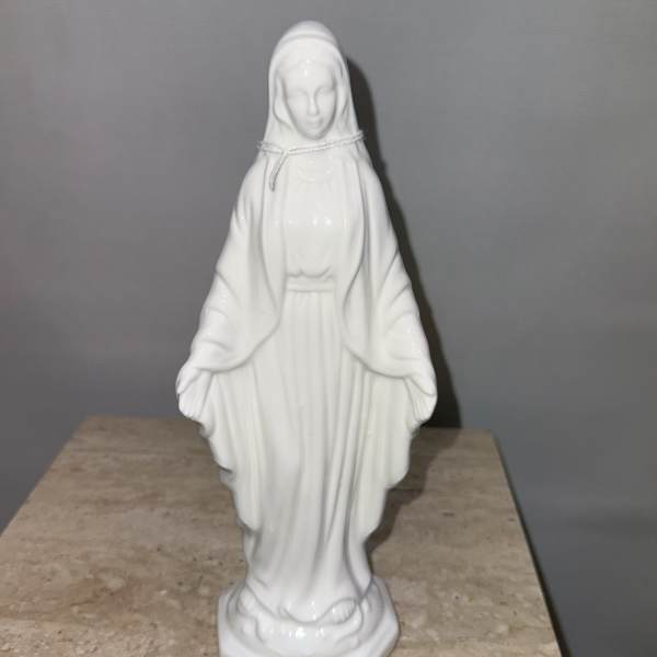 White religious statue of a robed woman standing on a base