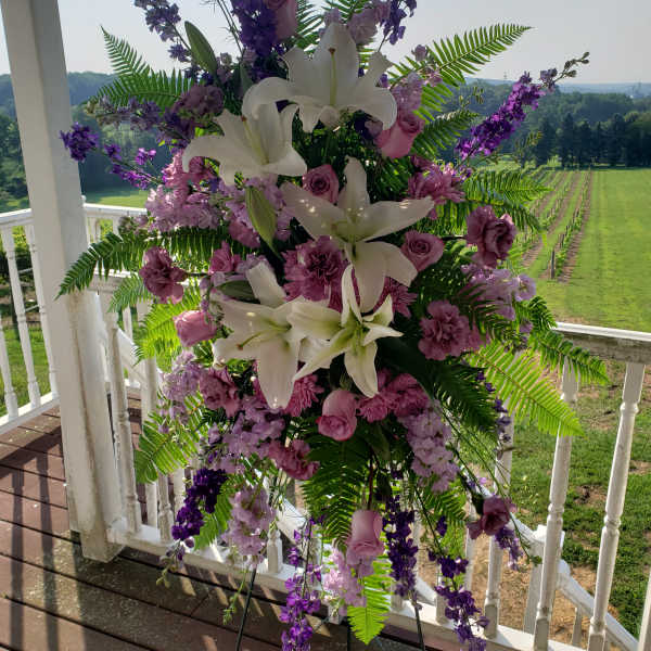 Tall floral standing spray with white lilies and purple blooms