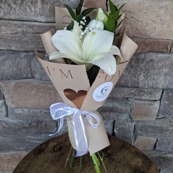 White lily bouquet wrapped in beige paper with a white ribbon