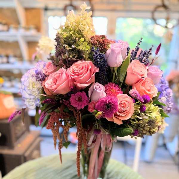 Bouquet of pink and lavender roses with mixed flowers in a glass vase