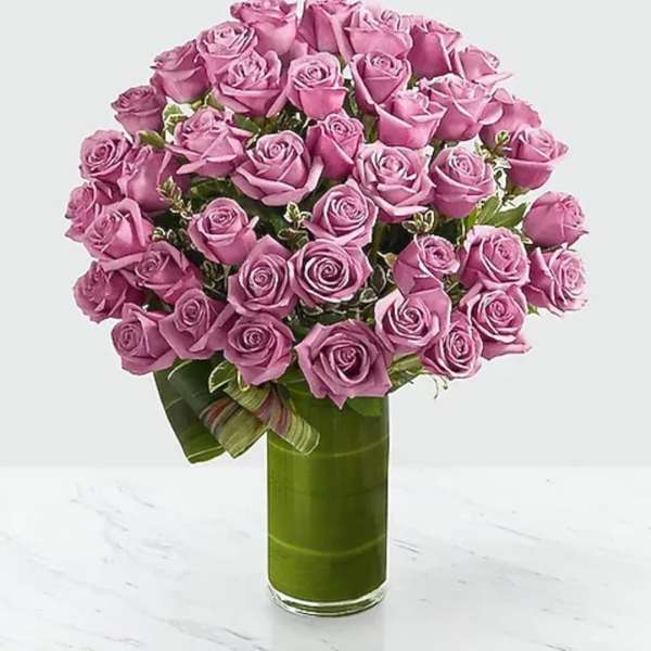 Pink rose bouquet in a tall green glass vase