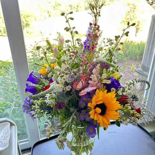 Mixed bouquet in a clear glass vase with a large yellow sunflower