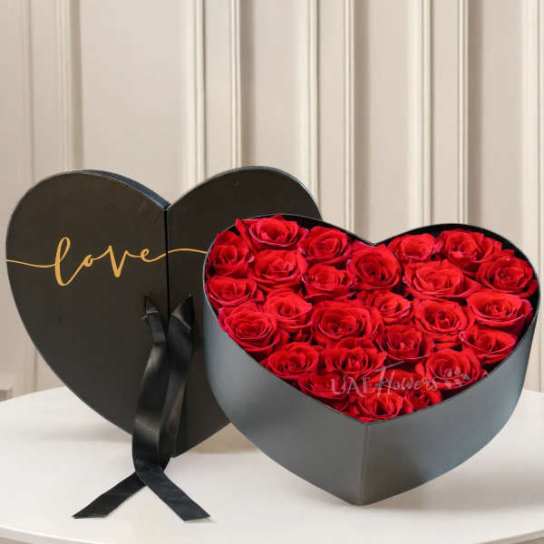 Heart-shaped box filled with red roses and a black ribbon