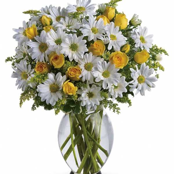 White daisies and yellow roses in a clear glass vase