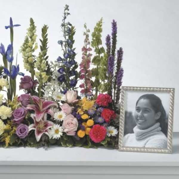 Colorful memorial floral arrangement beside a framed portrait
