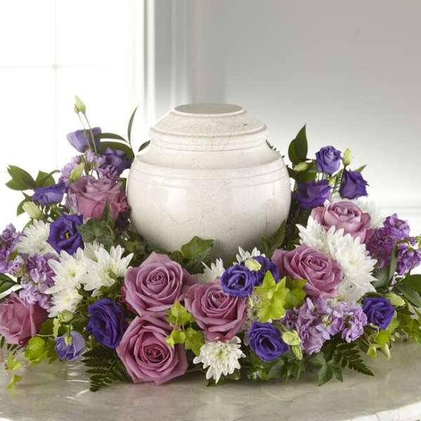 Purple and pink roses arranged around a white urn