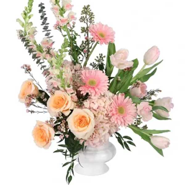 Pink and peach floral arrangement in a white pedestal vase
