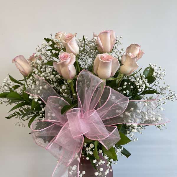 Pink roses and baby's breath in a mauve vase with a large pink bow