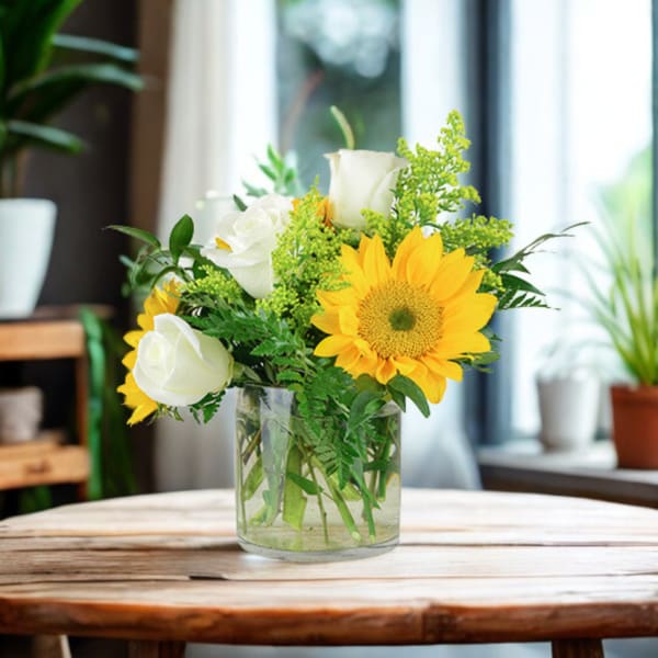 Sunflower and white rose arrangement in a clear glass vase